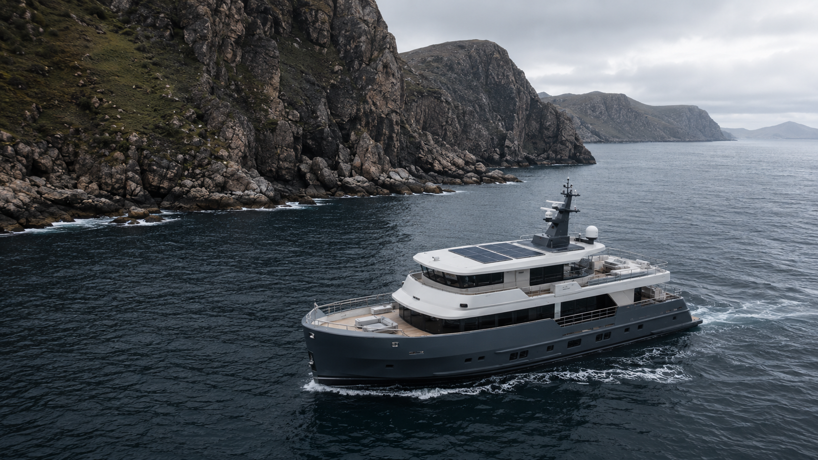 Expedition yacht with integrated solar panels cruising along a rugged coastline